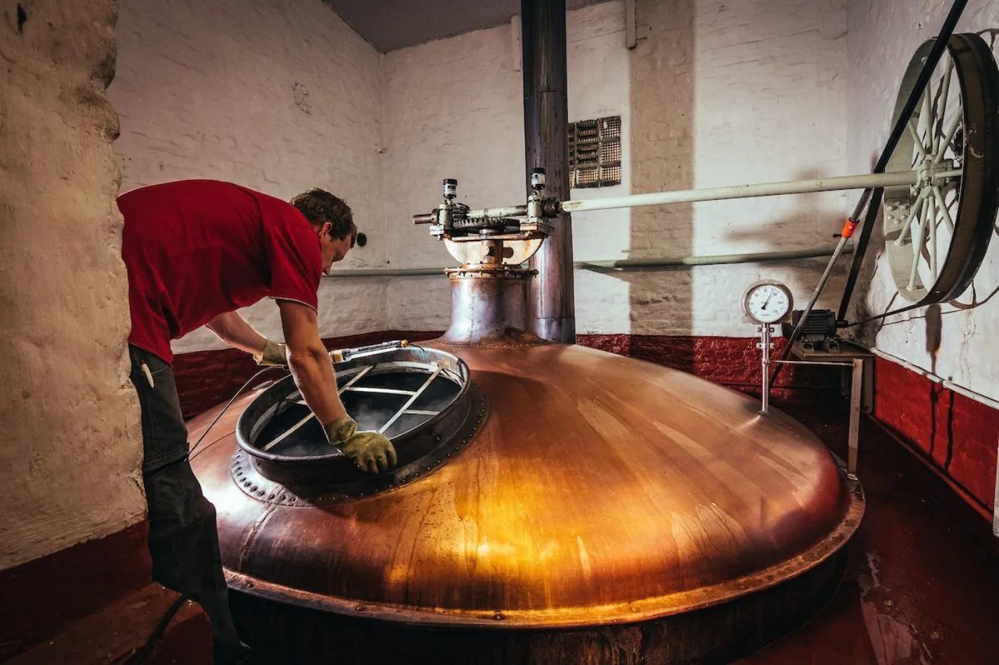 Brouwer aan het werk bij de koperen ketel in de brouwerij